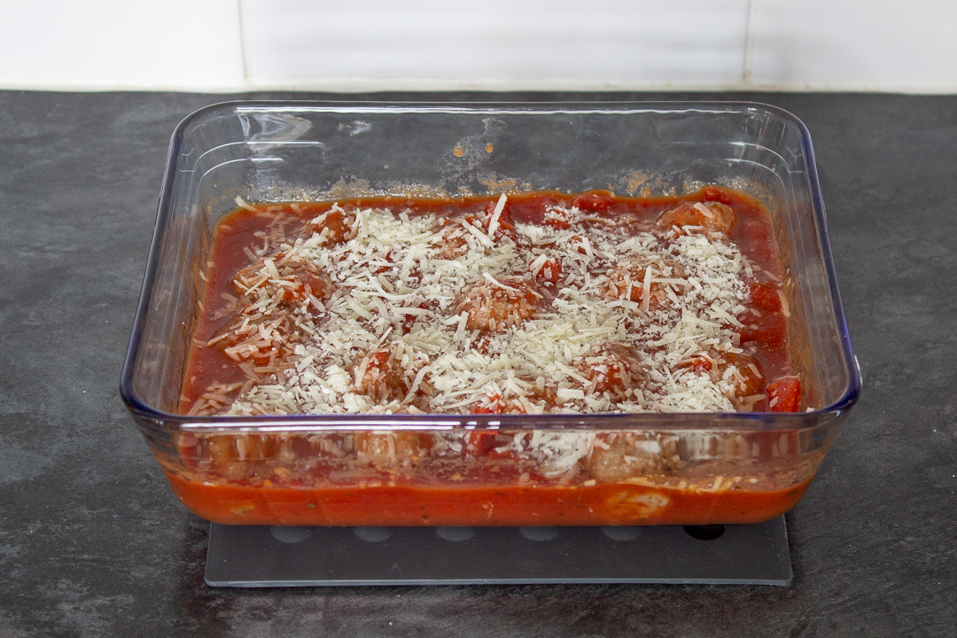 Meatballs in a tomato based sauce topped with grated parmesan cheese.