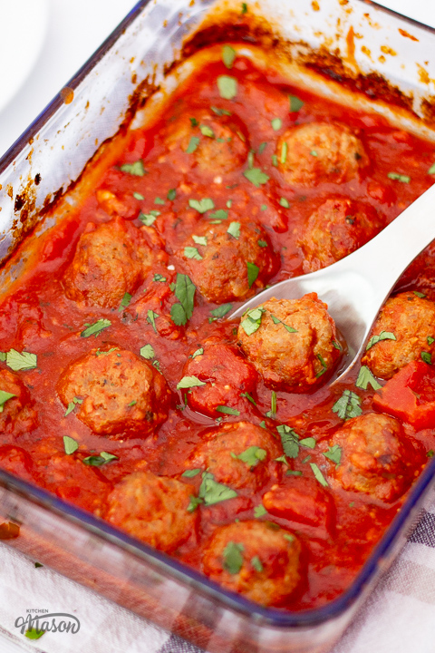 Tomato turkey meatballs in an oven proof dish with a fork.