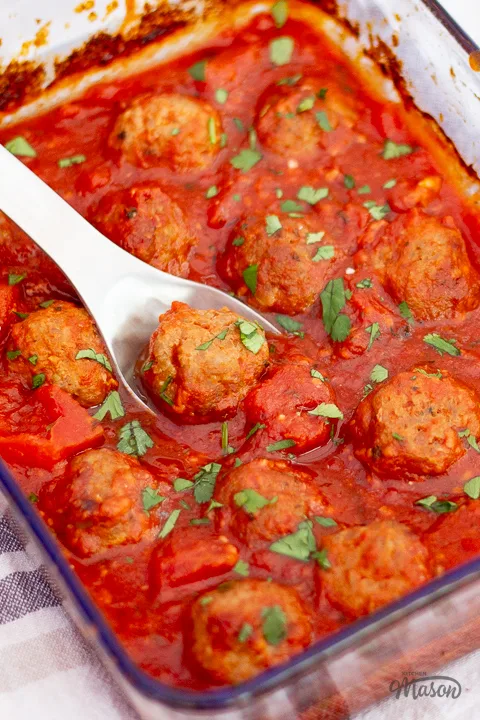 Oven baked turkey meatballs and homemade tomato sauce in a glass dish.