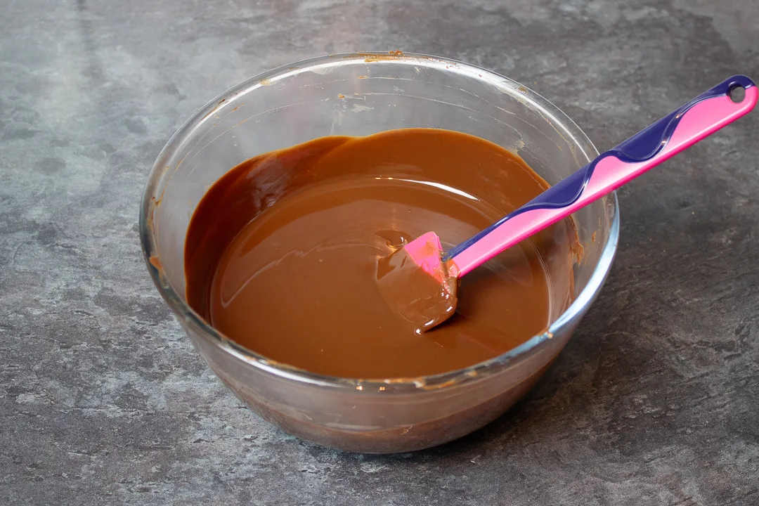 Melted chocolate, butter and golden syrup in a large mixing bowl with a spatula.