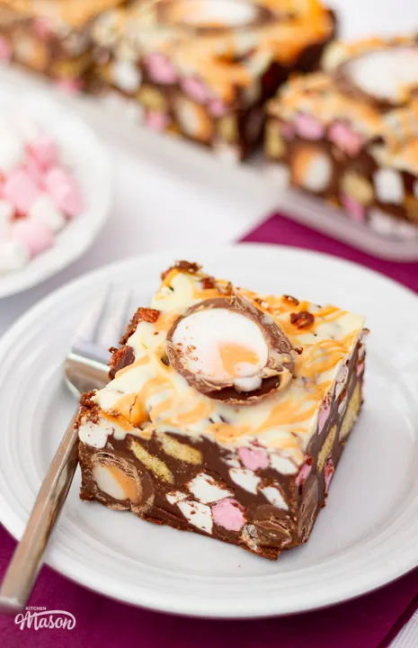 Close up of a Creme Egg rocky road bar on a small white plate with a fork.