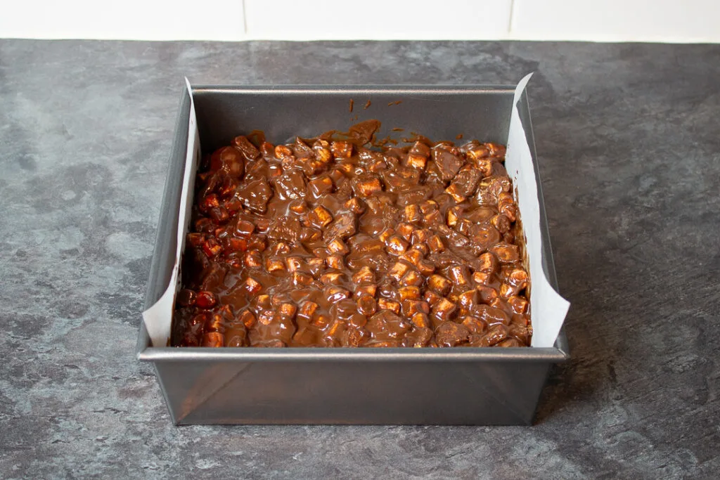 Rocky road mixture pressed into a lined baking tin.