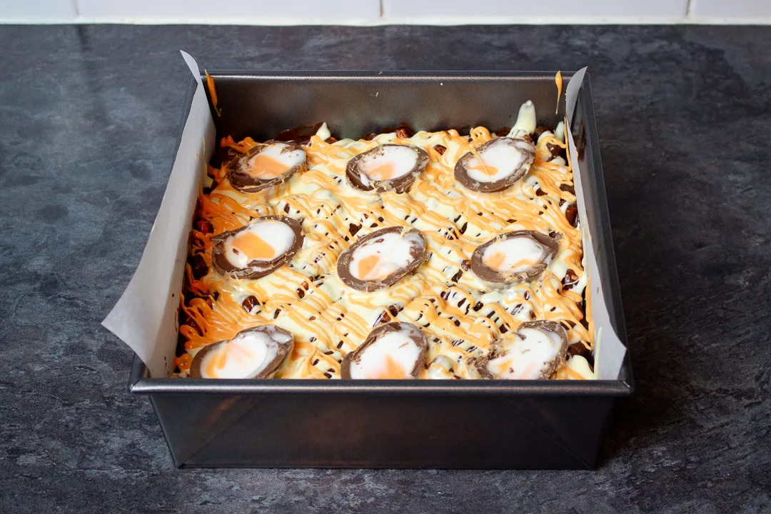 Creme Egg halves pressed into the top of the rocky road mixture in a baking tin.
