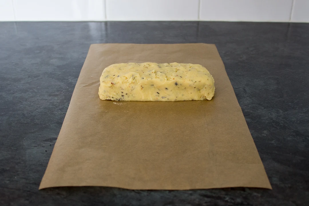 Cracker dough rolled into a log on a sheet of baking paper.