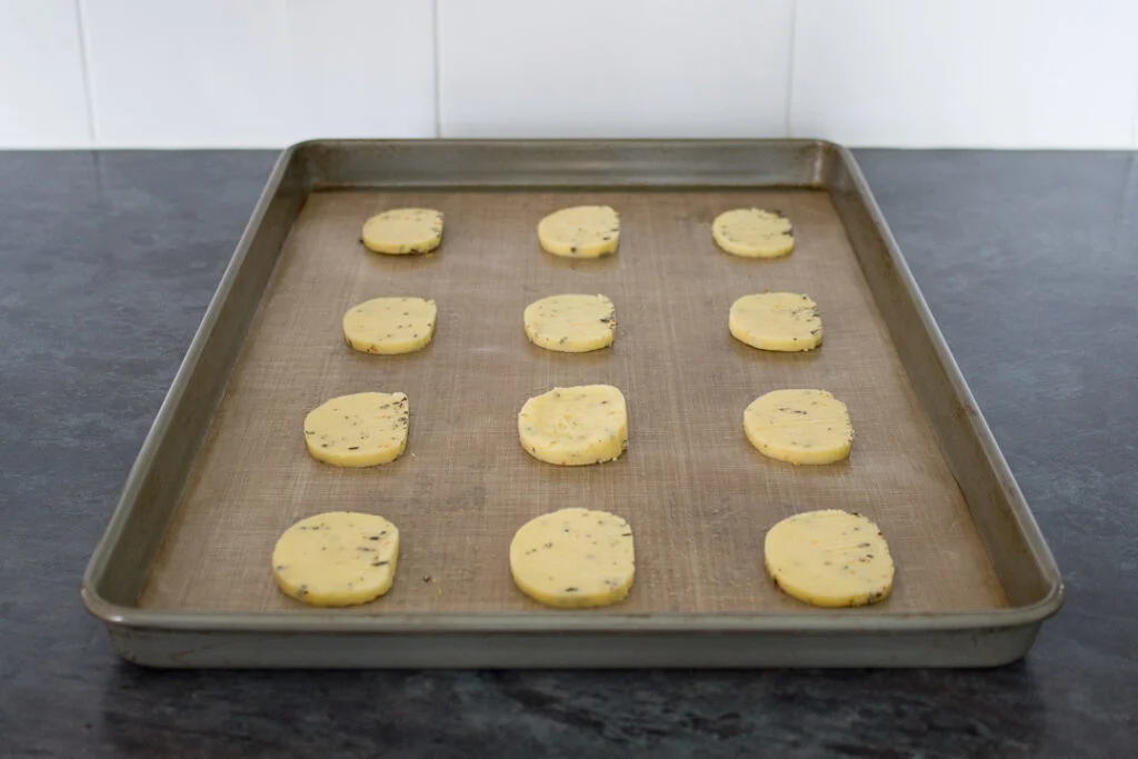 Unbaked spicy rosemary crackers on a lined baking tray.