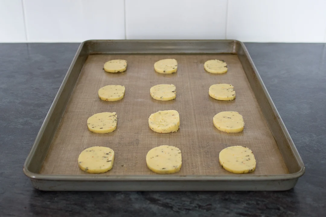 Unbaked spicy rosemary crackers on a lined baking tray.