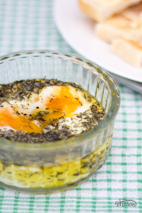 Thyme baked eggs in a ramekin with a plate of buttered toast to the side.