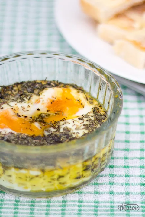 Thyme baked eggs in a ramekin with a plate of buttered toast to the side.