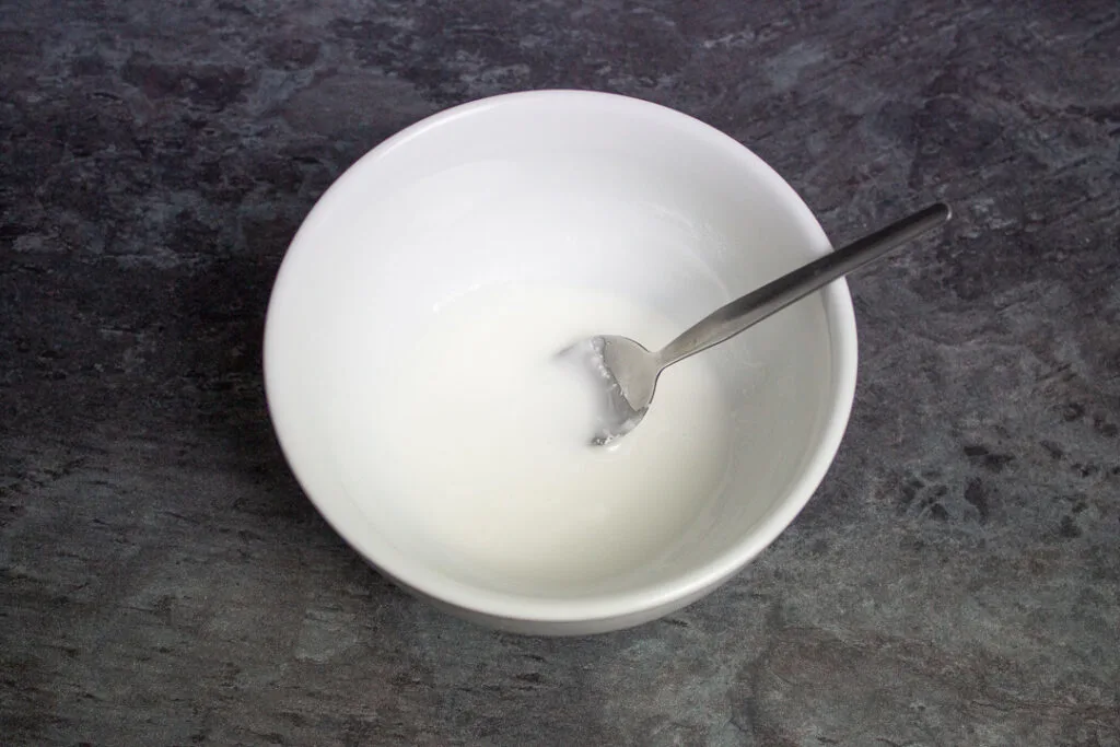 A small bowl filled with runny white icing.