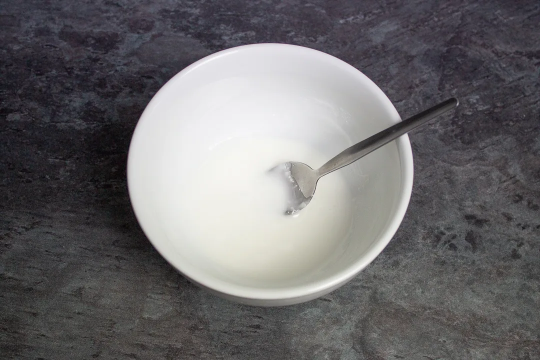 A small bowl filled with runny white icing.