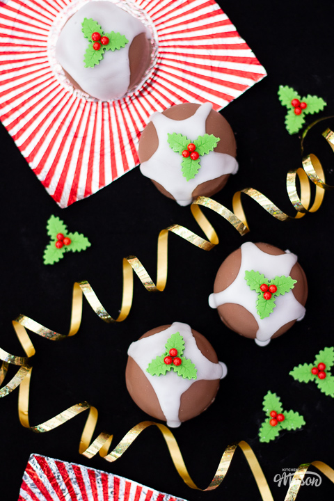 4 Tunnocks teacakes made to look like Christmas puddings, with holly and ivy sugar decorations around them.