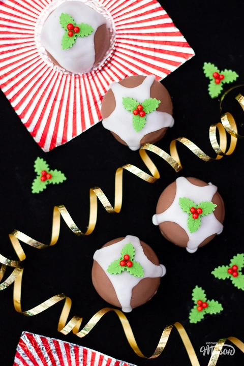 4 Tunnocks teacakes made to look like Christmas puddings, with holly and ivy sugar decorations around them.