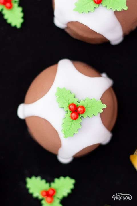 Close up of a single Christmas pudding teacake topped with a holly and ivy sugar decoration.