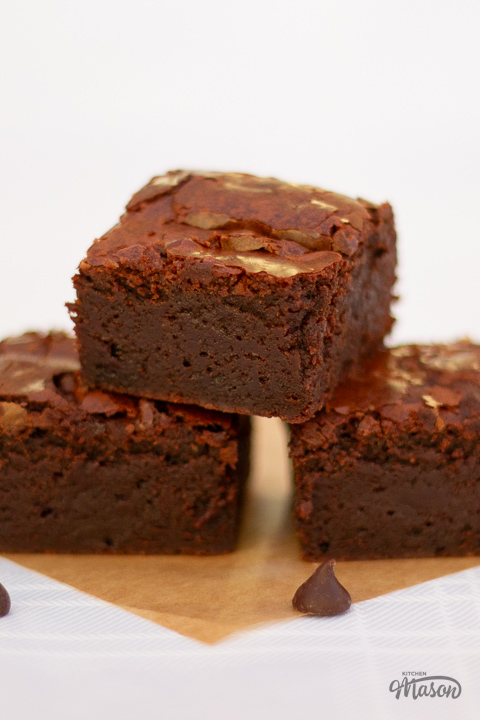 Chocolate brownies in a tower on a square of baking paper.
