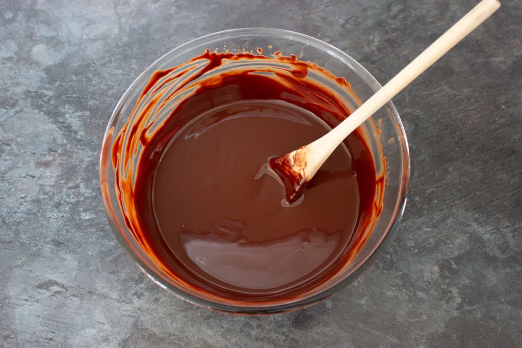 A large mixing bowl filled with melted dark chocolate, milk chocolate and butter.