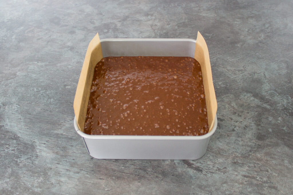 Unbaked ultimate chocolate brownie batter in a lined baking tin.