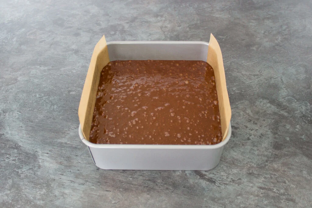 Unbaked ultimate chocolate brownie batter in a lined baking tin.