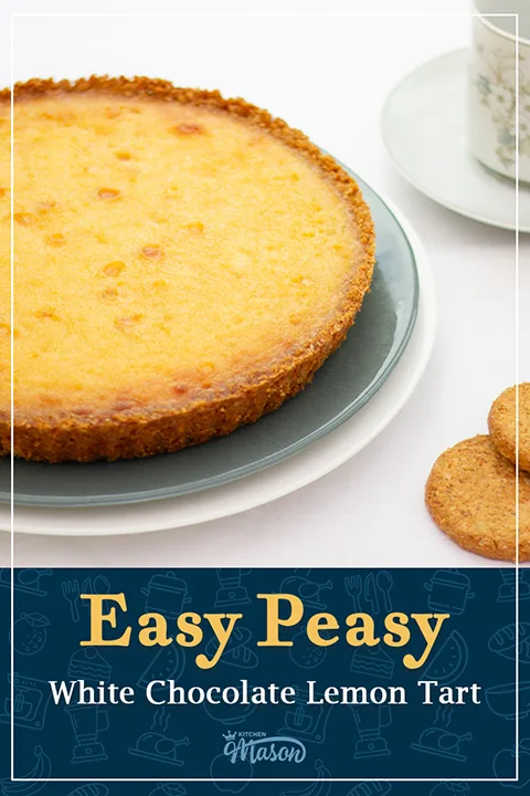 A white chocolate lemon tart on a serving plate, with a cup of tea and spare biscuits to the side. A text overlay says "Easy peasy white chocolate lemon tart".