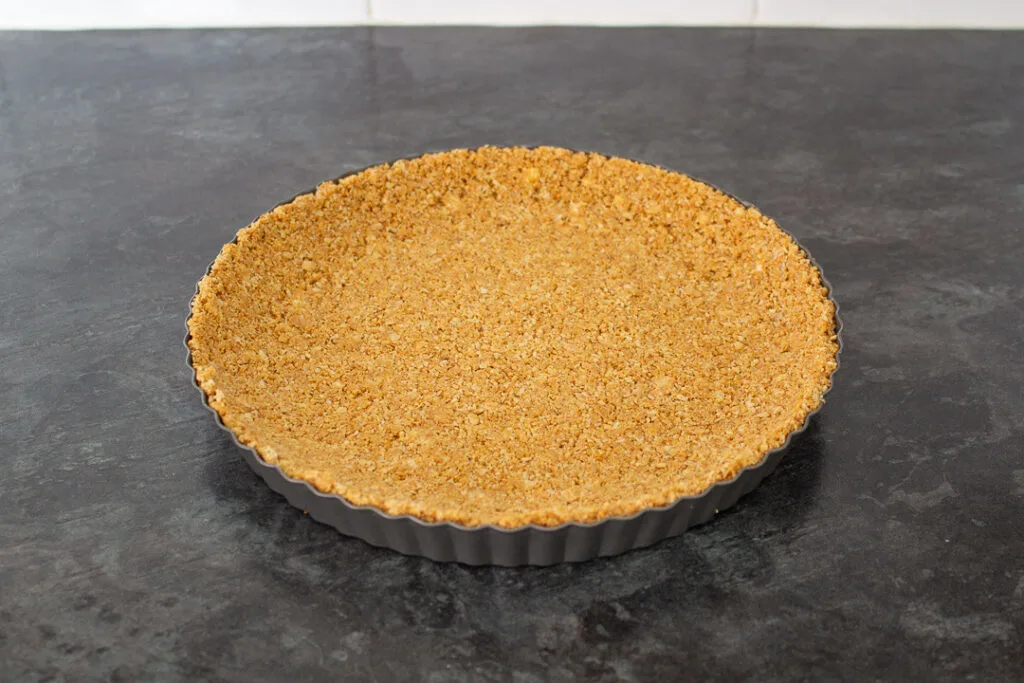 Biscuit and butter crumb base pressed into a fluted tart tin.