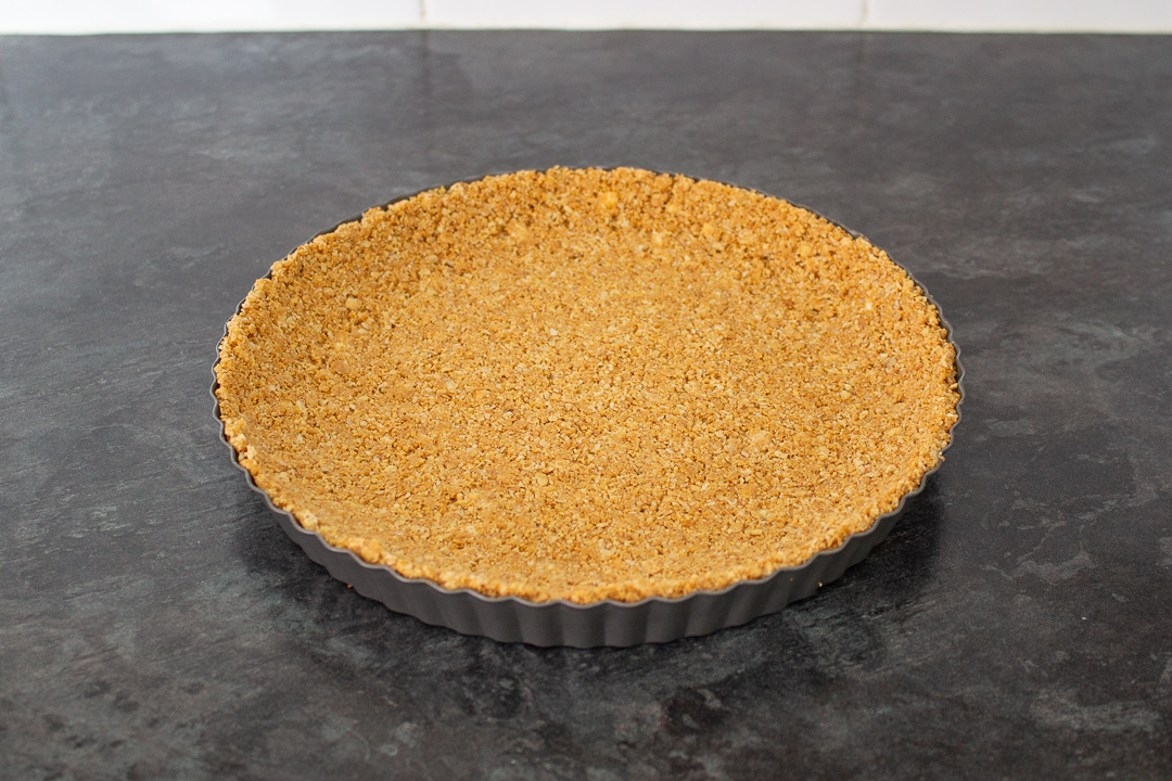 Biscuit and butter crumb base pressed into a fluted tart tin.