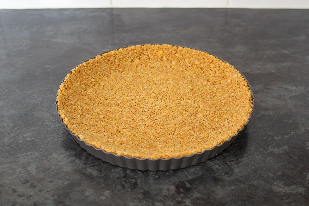 Biscuit and butter crumb base pressed into a fluted tart tin.