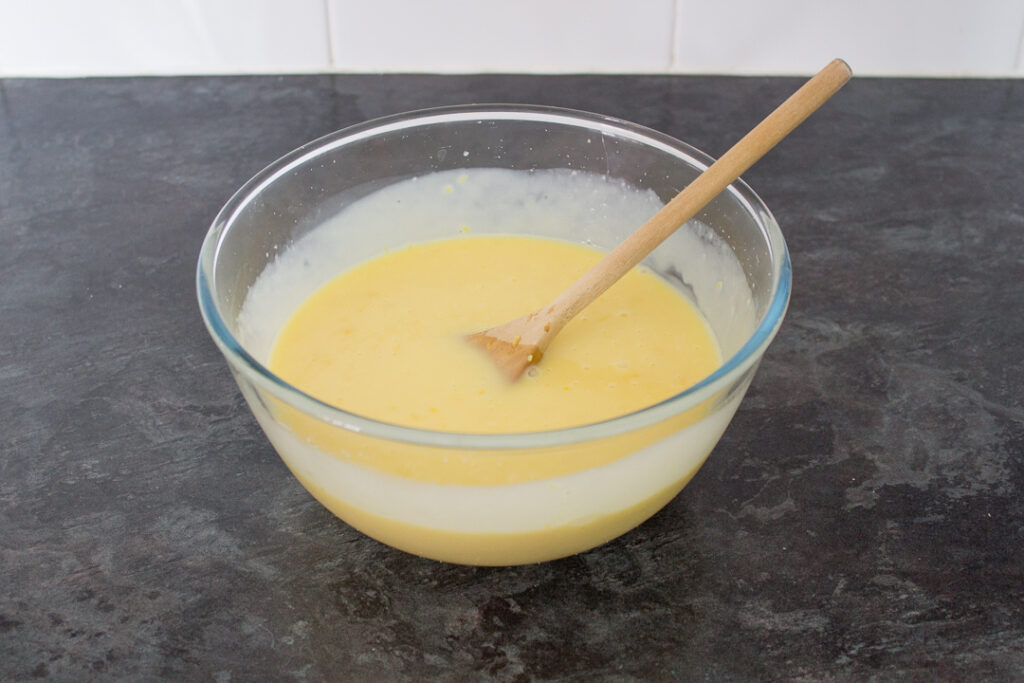 The lemon white chocolate ganache filling in a large mixing bowl with a wooden spoon.