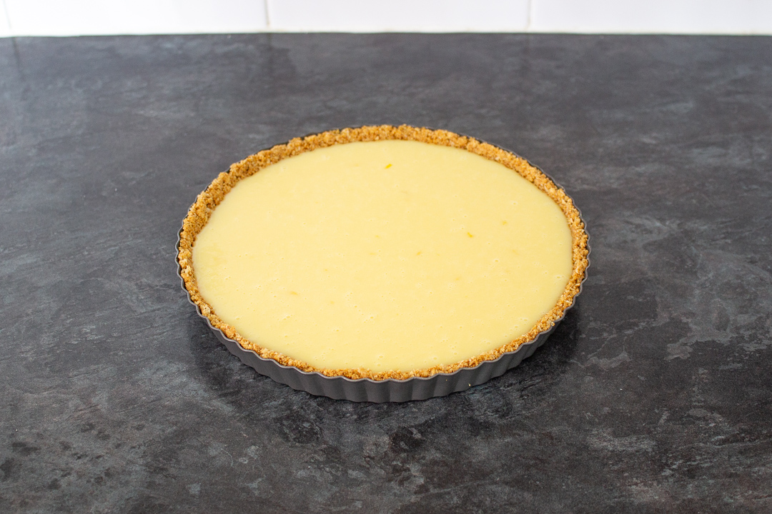 The completed white chocolate lemon tart in a fluted loose bottom tart tin.