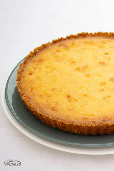 A whole white chocolate lemon tart on top of two stacked serving plates.