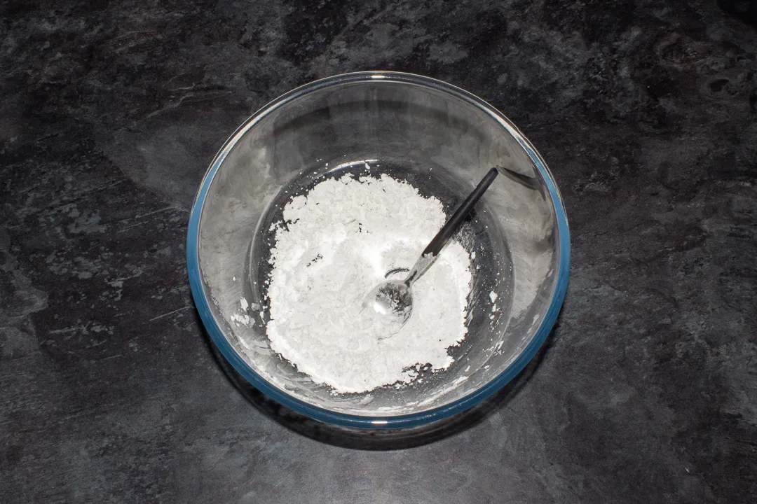 Seasoned cornflour in a bowl with a spoon.