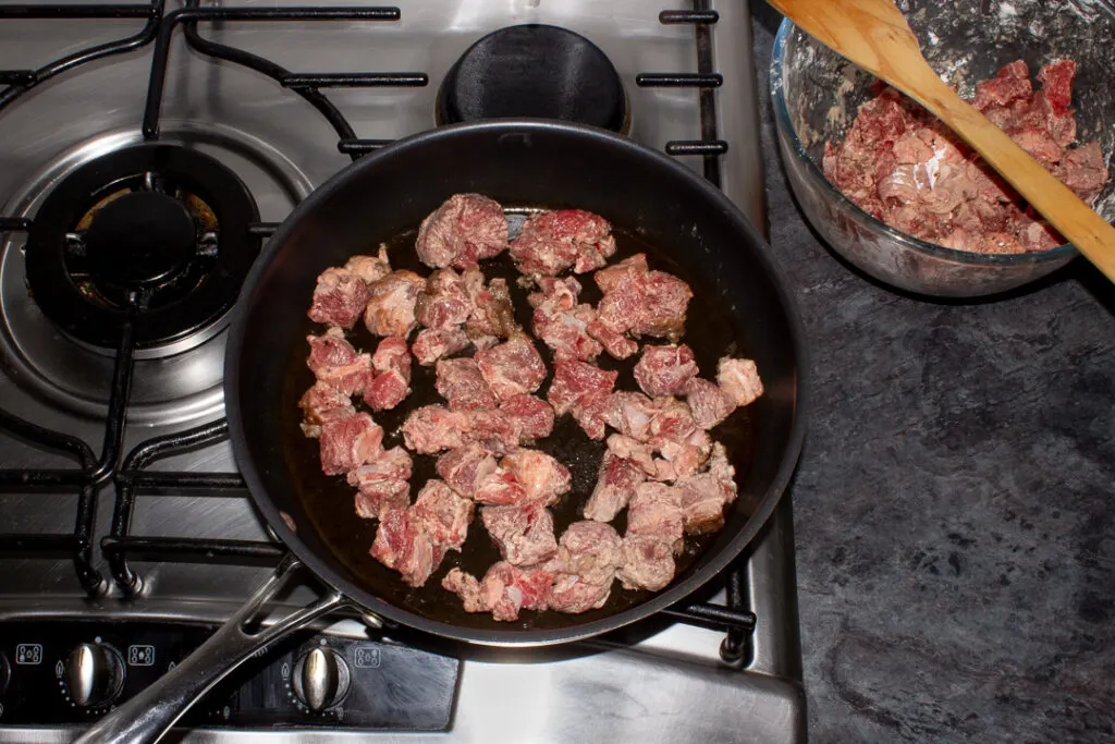 Diced beef browning in a frying pan.