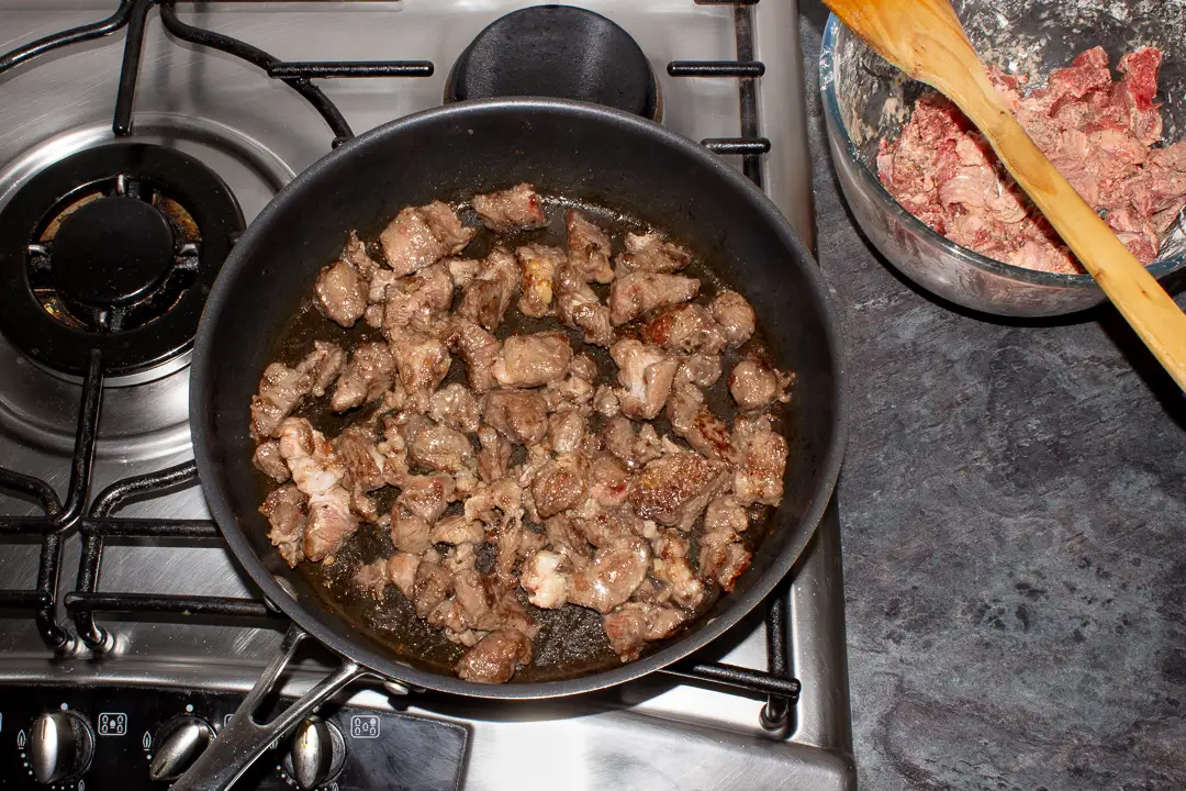 Browned diced beef in a frying pan.
