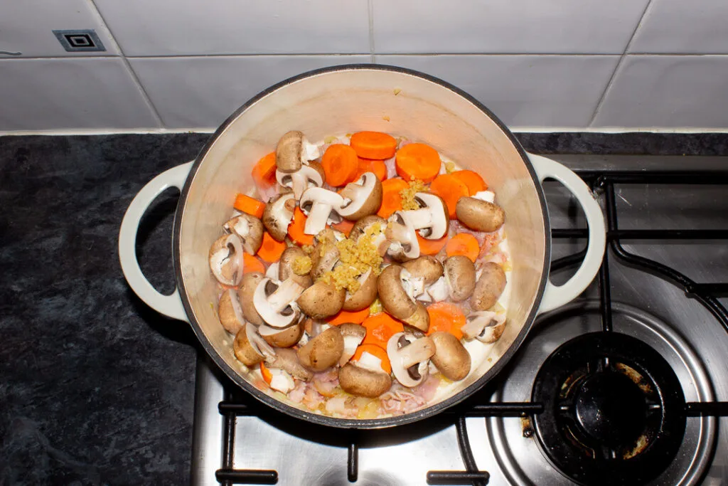 Beef casserole vegetable base ingredients cooking in a large casserole dish.