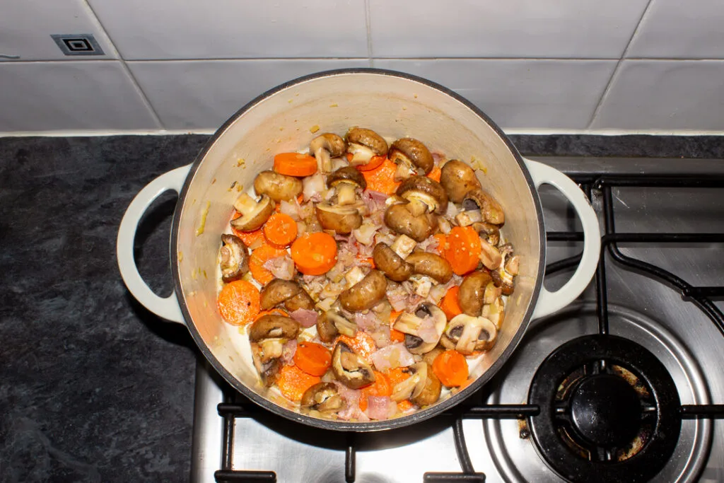 Beef casserole vegetable base ingredients cooking in a large casserole dish.