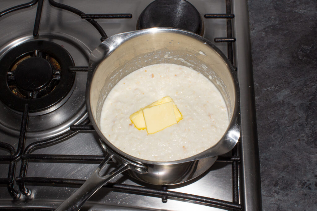 Butter melting into bread sauce in a saucepan on the stove top.