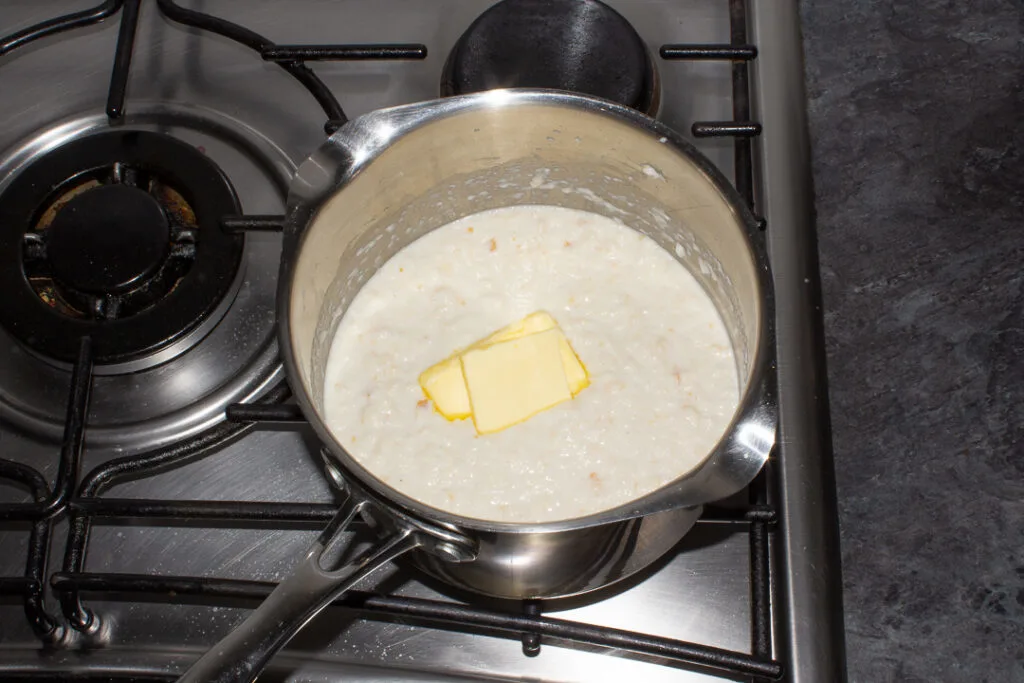 Butter melting into bread sauce in a saucepan on the stove top.
