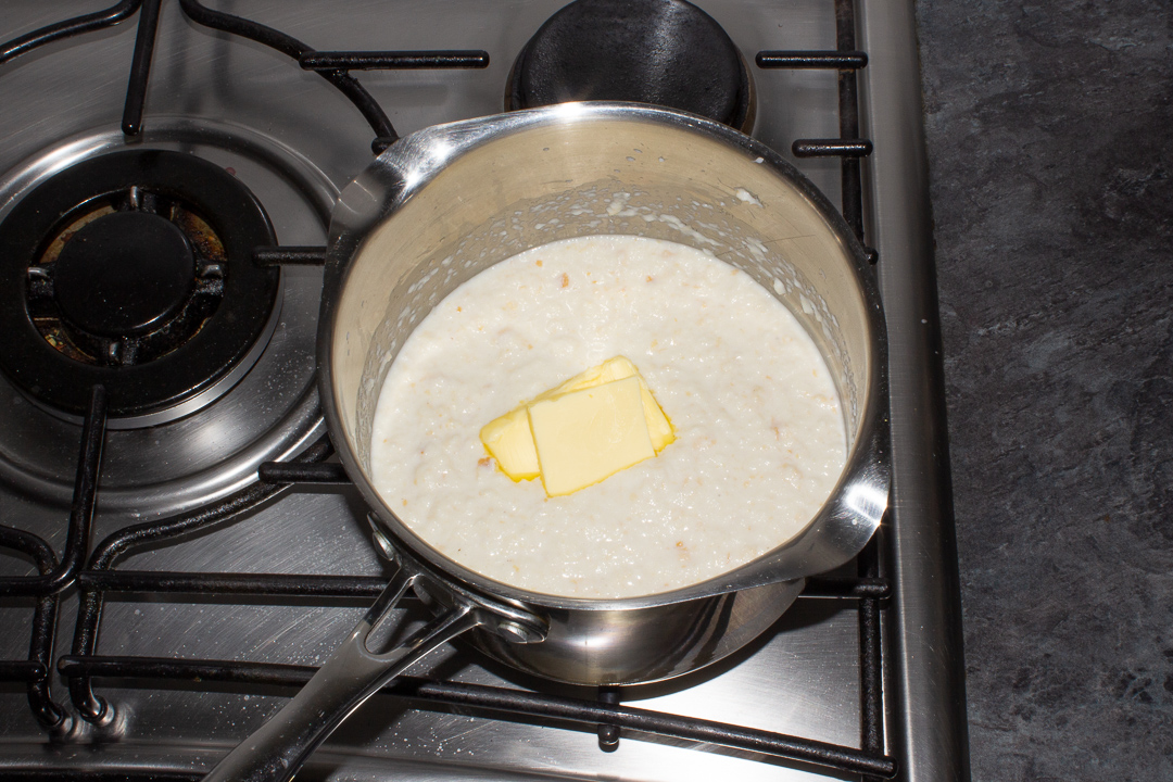 Butter melting into bread sauce in a saucepan on the stove top.