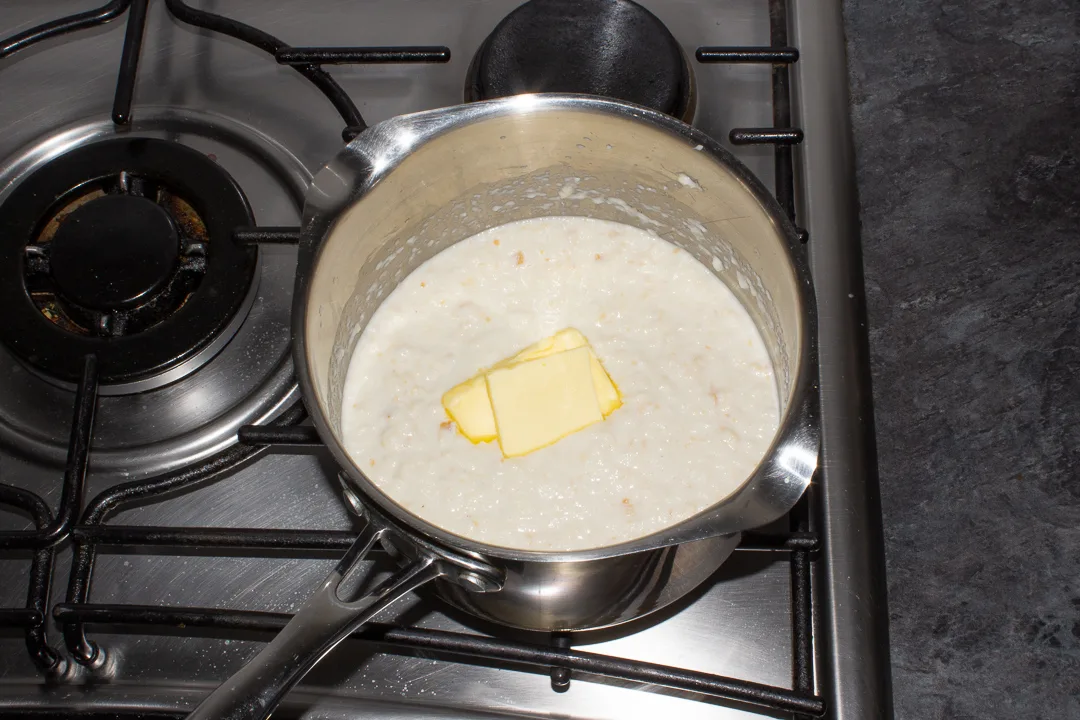 Butter melting into bread sauce in a saucepan on the stove top.