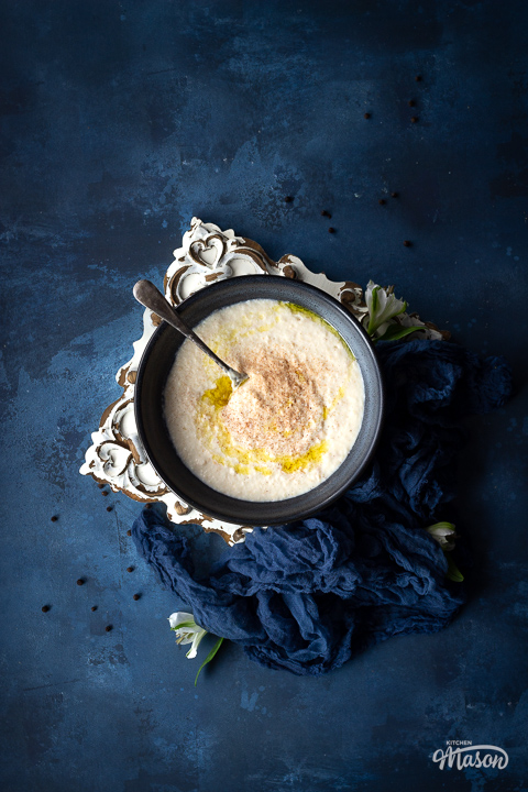 A large blue bowl filled with bread sauce, topped with melted butter and grated nutmeg.