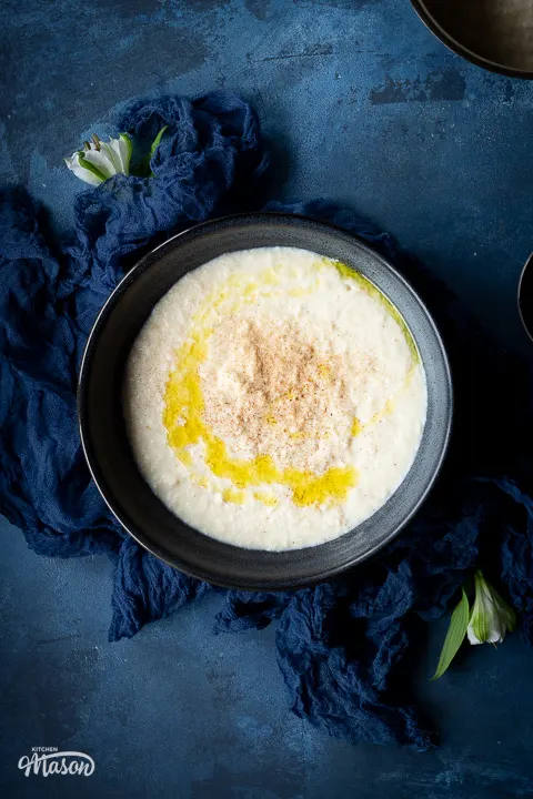 Close up of a large bowl of bread sauce topped with melted butter and freshly grated nutmeg.
