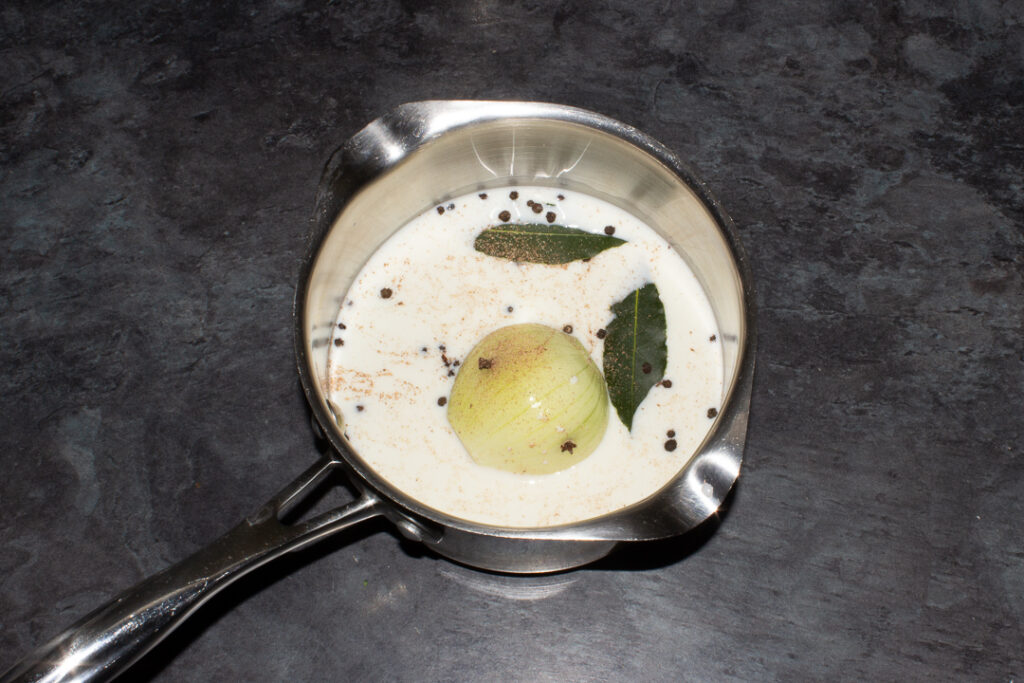 Milk, onion and spices in a saucepan.