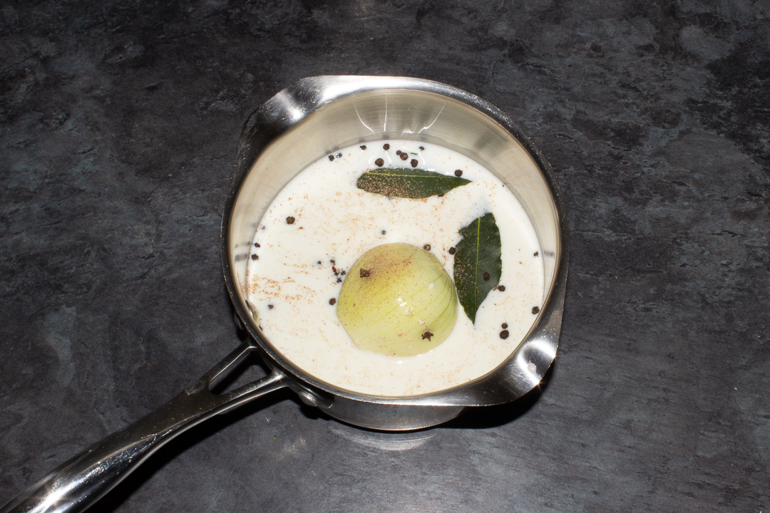 Milk, onion and spices in a saucepan.