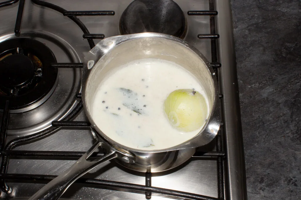Boiled milk, onion and spices in a saucepan on the stove top.
