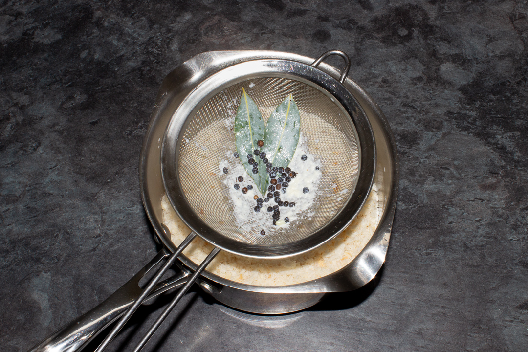 A sieve over a saucepan that's had the infused milk poured through it.