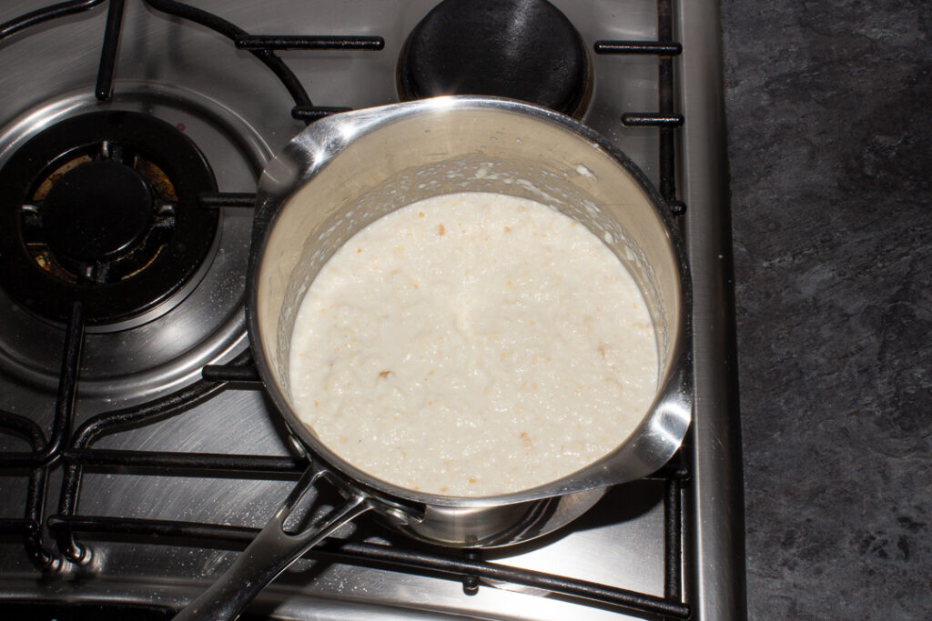 Bread sauce heating up in a saucepan on the stove top.