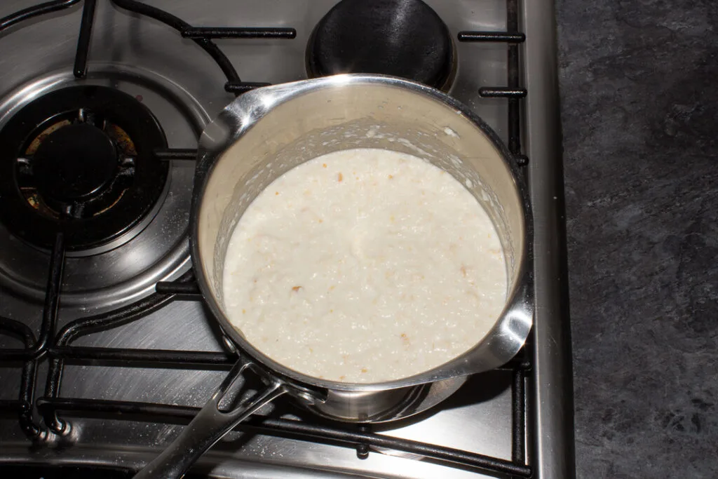 Bread sauce heating up in a saucepan on the stove top.