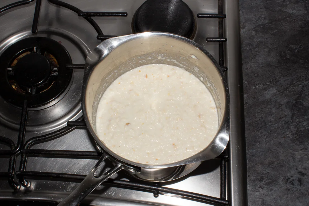 Bread sauce heating up in a saucepan on the stove top.