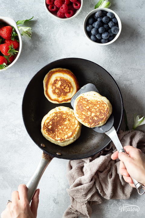 Someone flipping a drop scone in a frying pan.