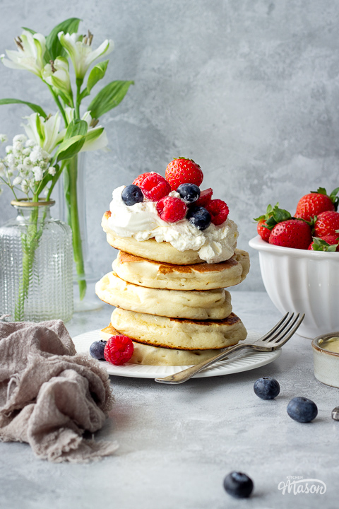 A stack of drop scones topped with whipped cream and berries.