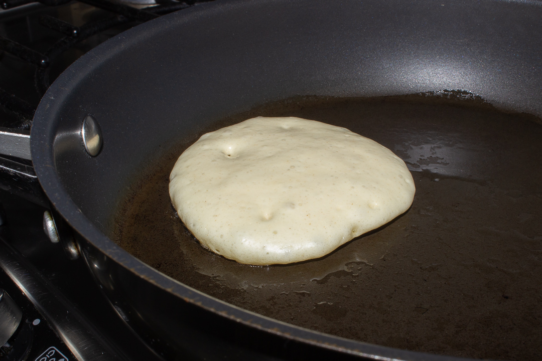 Part cooked drop scone in a frying pan.