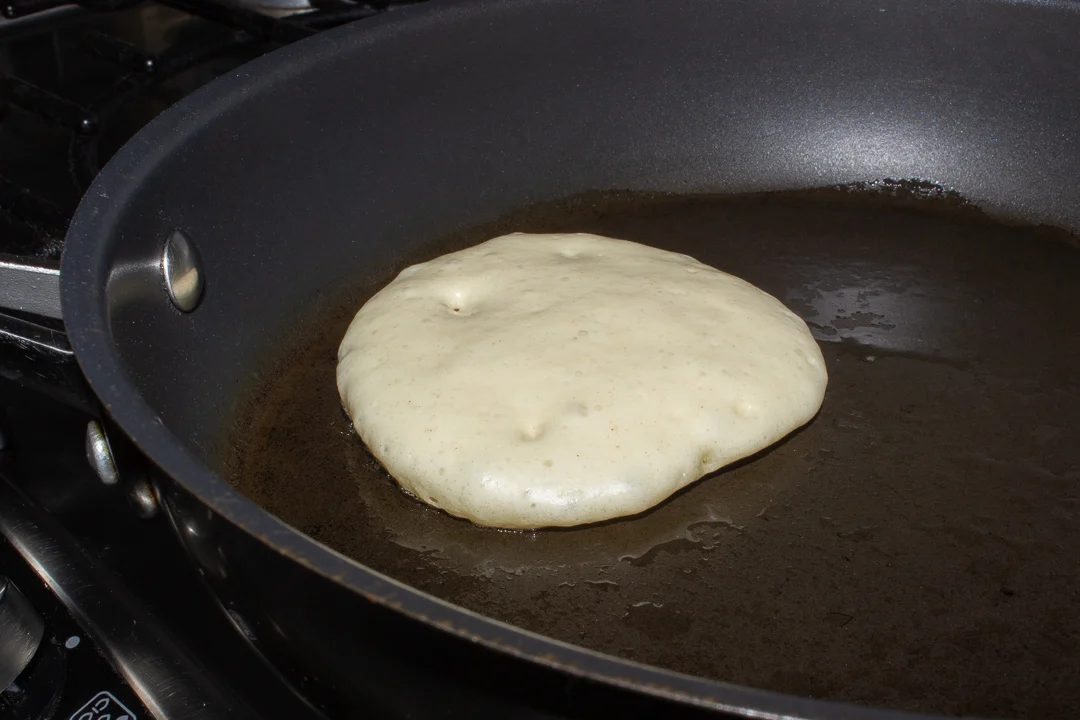 Part cooked drop scone in a frying pan.